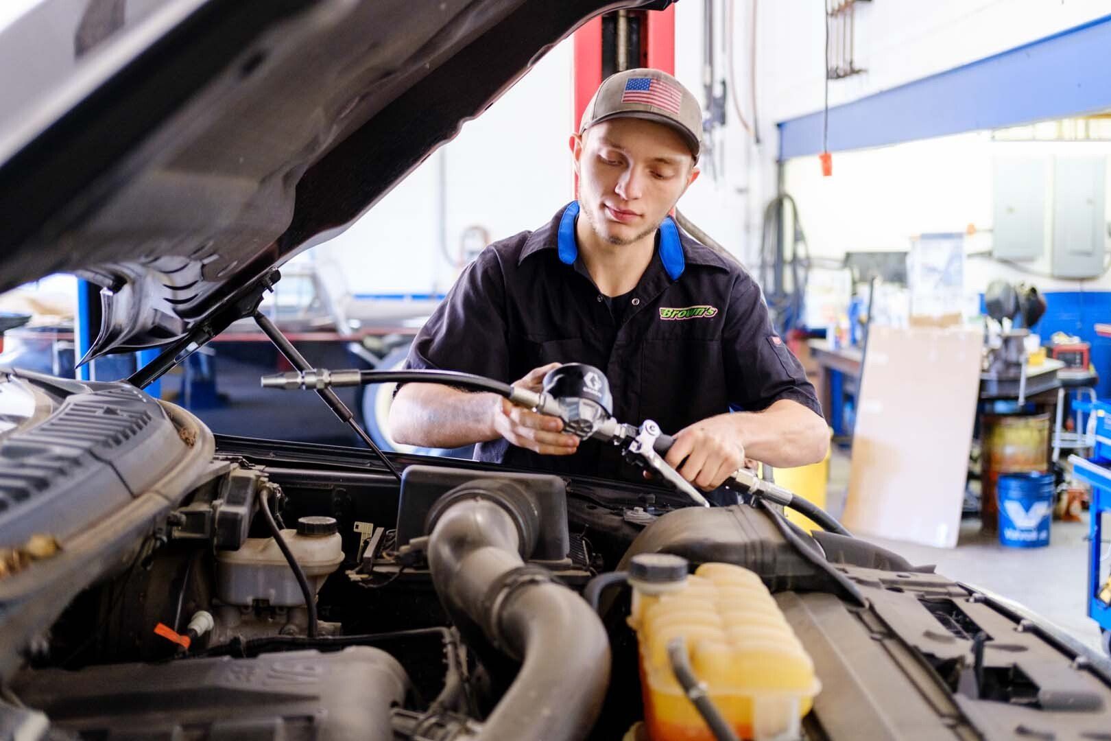 Mechanic working on a car engine in a repair shop.