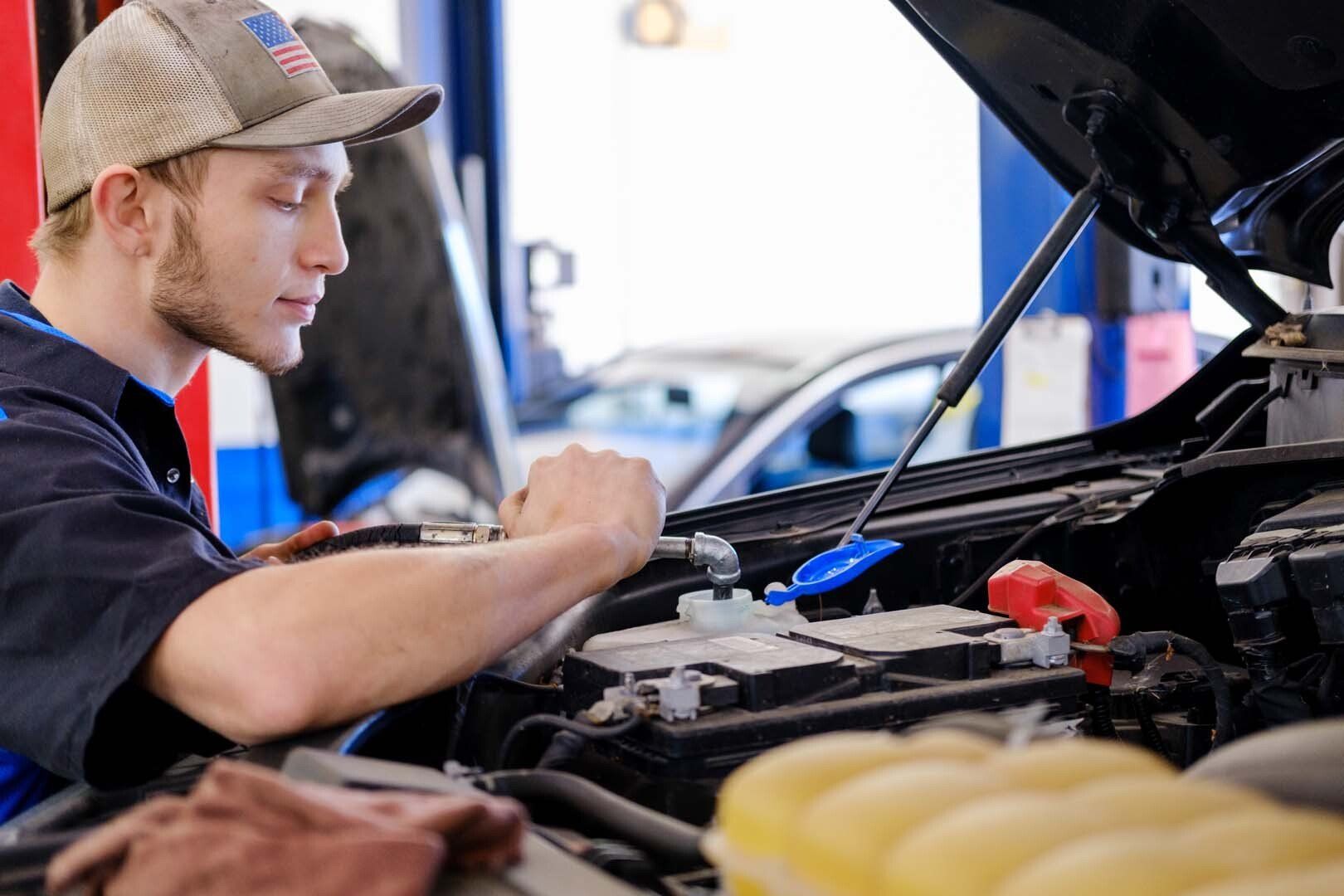 Mechanic working on a car engine in a repair shop.