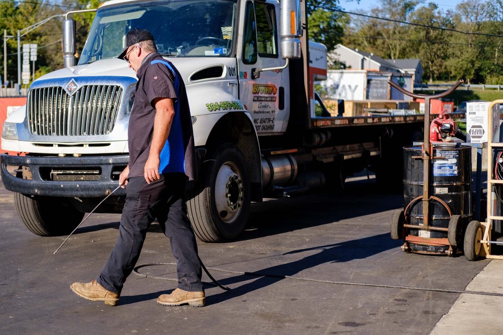 Mechanic walking toward truck; truck parked outside building; sunny day.