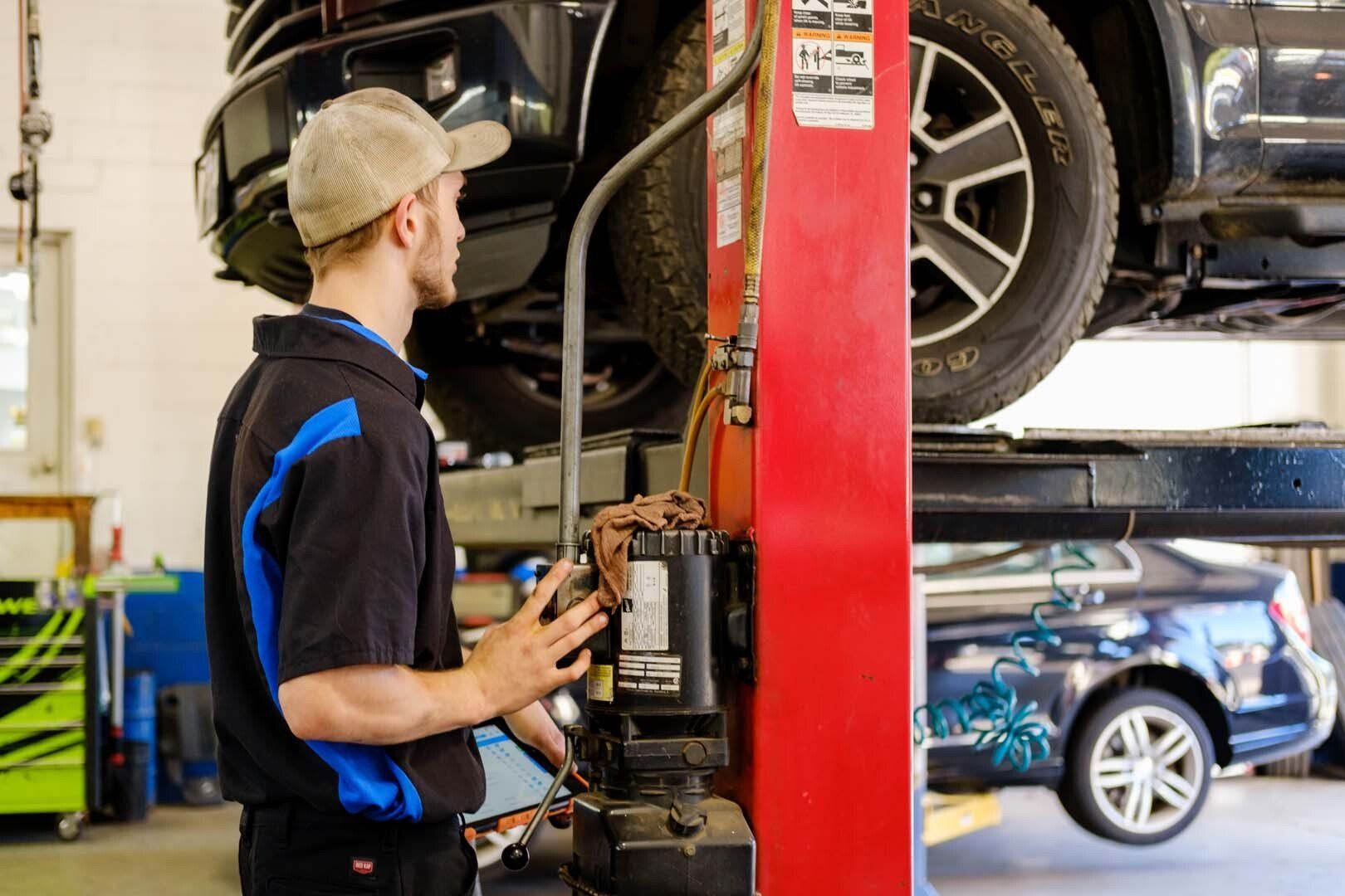 Mechanic working on a car raised on a lift in a garage.