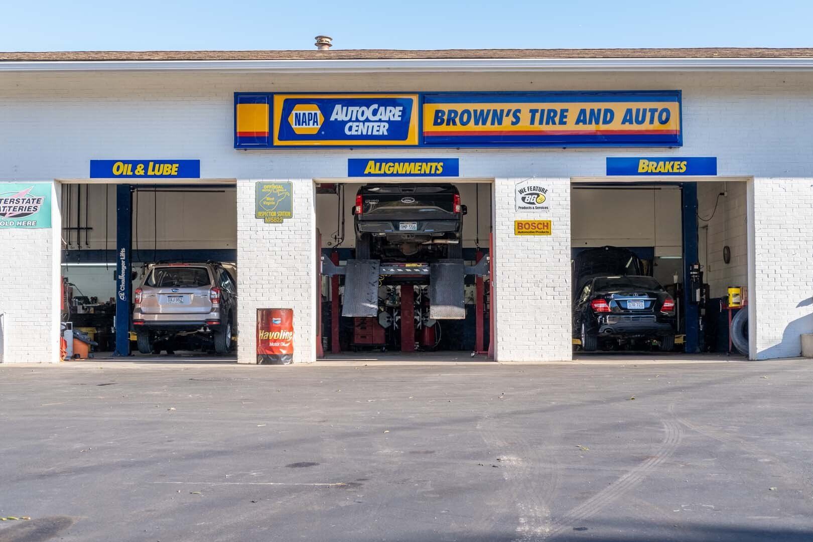 Brown's Tire and Auto shop with bays. Cars on lifts inside. Yellow and blue signage.
