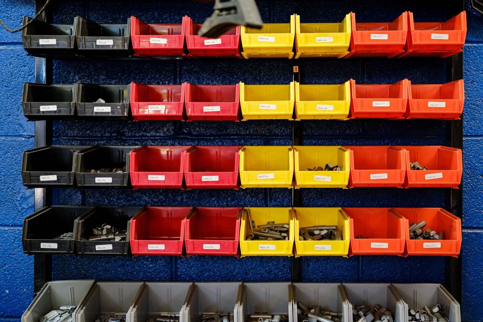 Rows of black, red, and yellow storage bins on a blue wall.