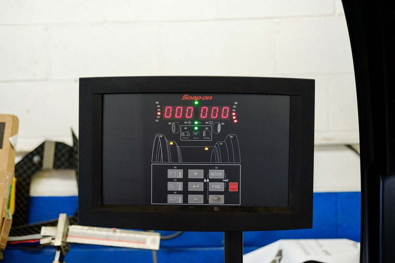 Snap-on wheel alignment machine display with red digital numbers and green indicator lights.