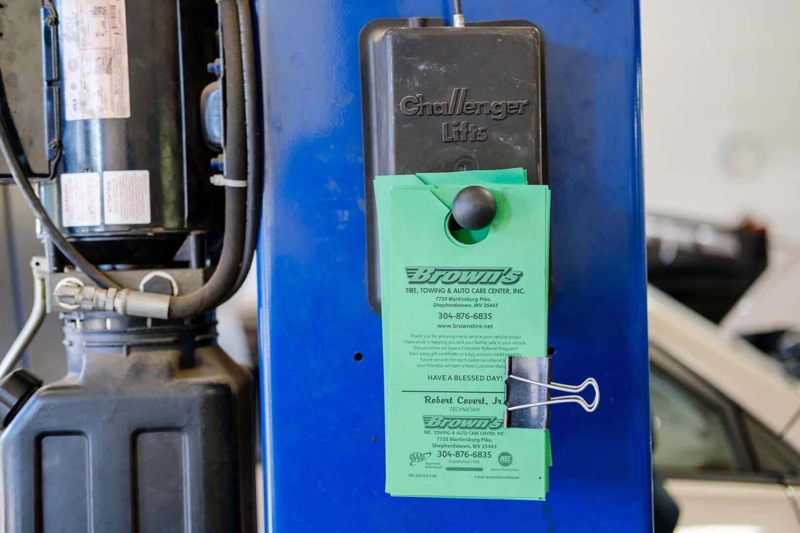 Green service tag clipped to a blue lift column in a garage setting.
