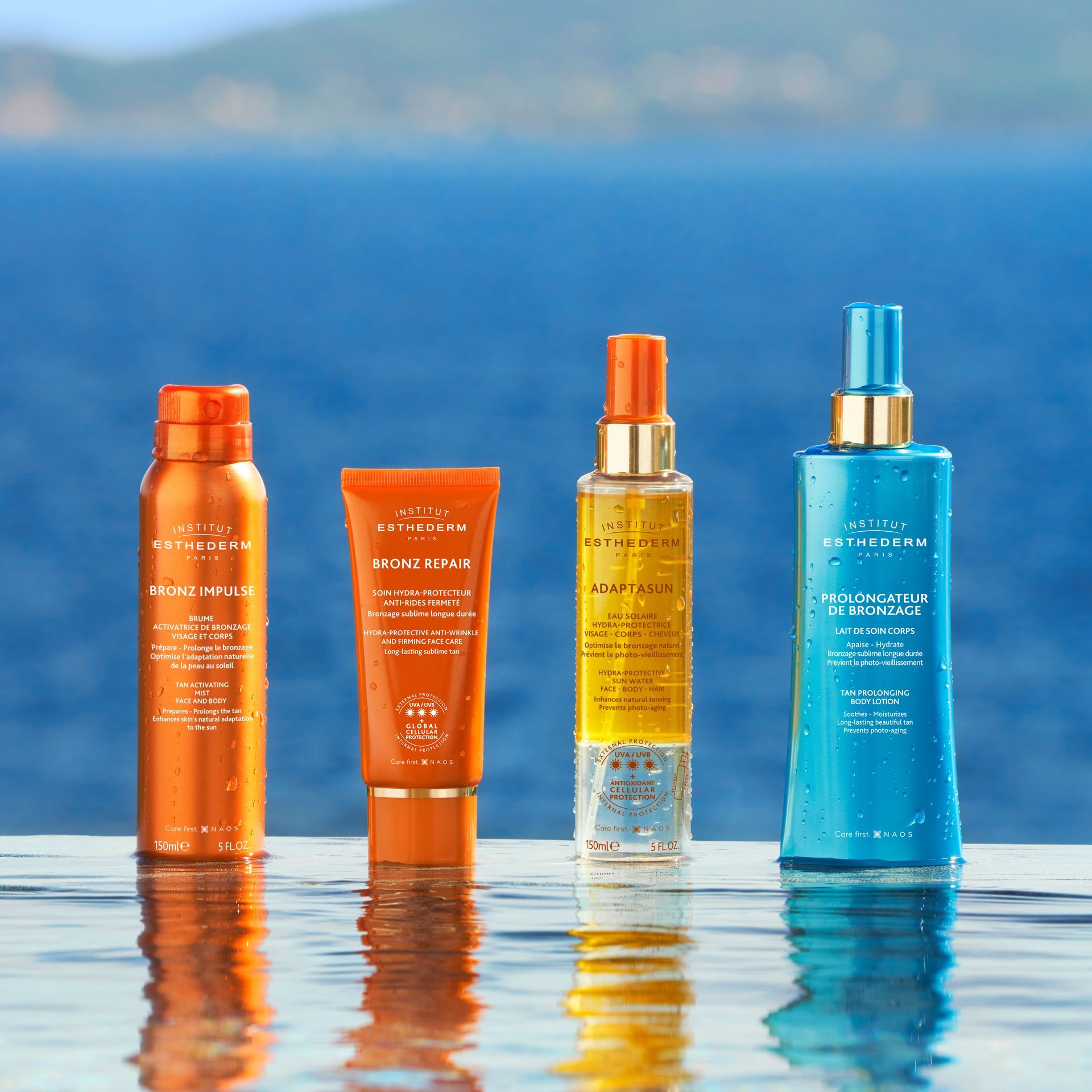Quattro bottiglie di crema solare sul bordo di una piscina, con il mare blu sullo sfondo.