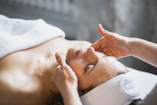 Donna che riceve un massaggio al viso con le mani sulla fronte, in un centro benessere.