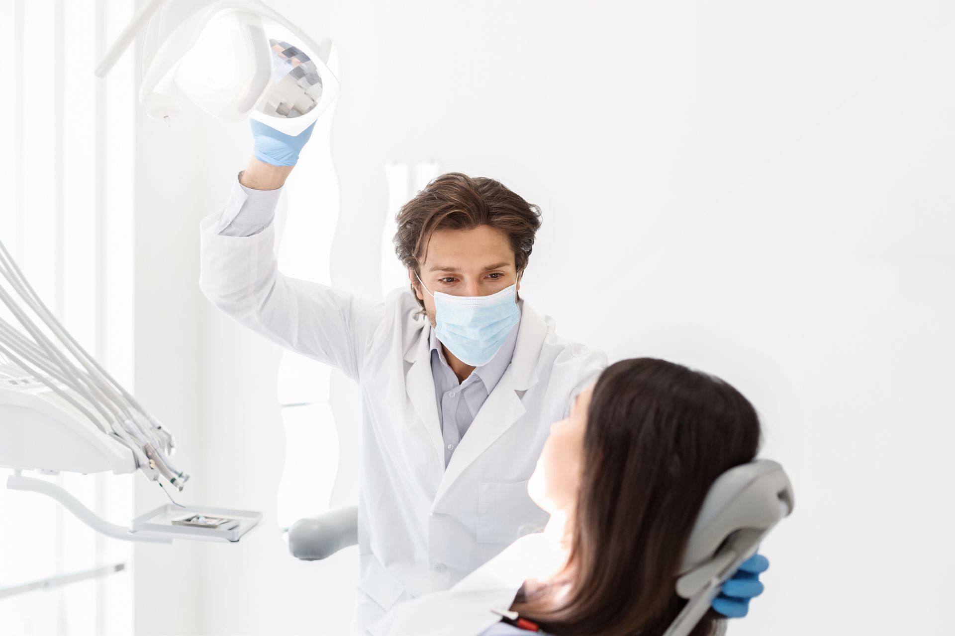 A dentist is talking to a patient in a dental chair.