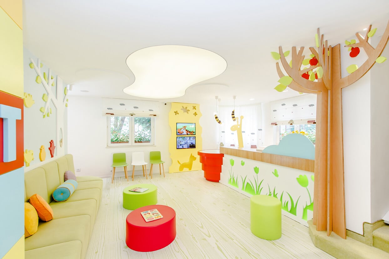 A waiting room with colorful furniture and a tree on the wall.