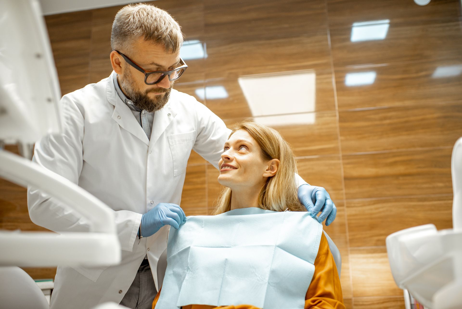 A dentist is examining a woman 's teeth in a dental office.