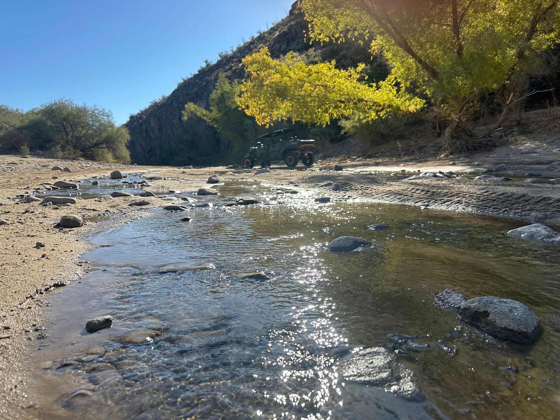 A river flowing through a rocky area with a jeep in the background.
