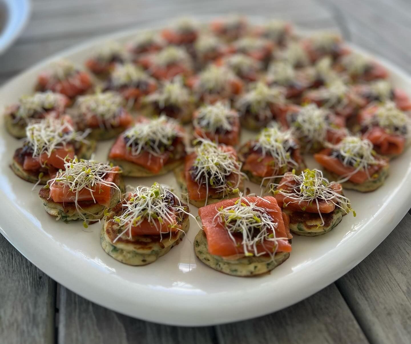 A white plate topped with appetizers on a wooden table. — Coastal Catering in North Avoca, NSW