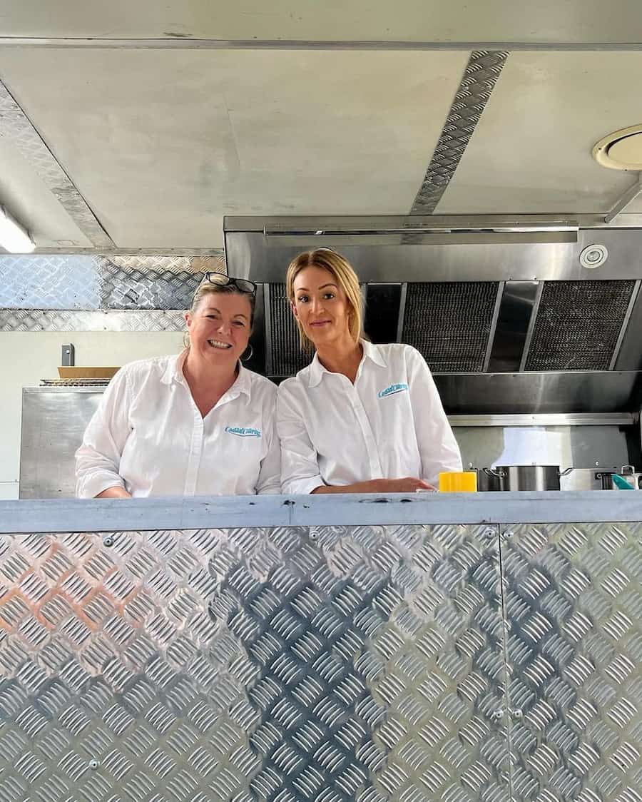 Two Women Are Standing Next to Each Other in a Kitchen — Coastal Catering in North Avoca, NSW