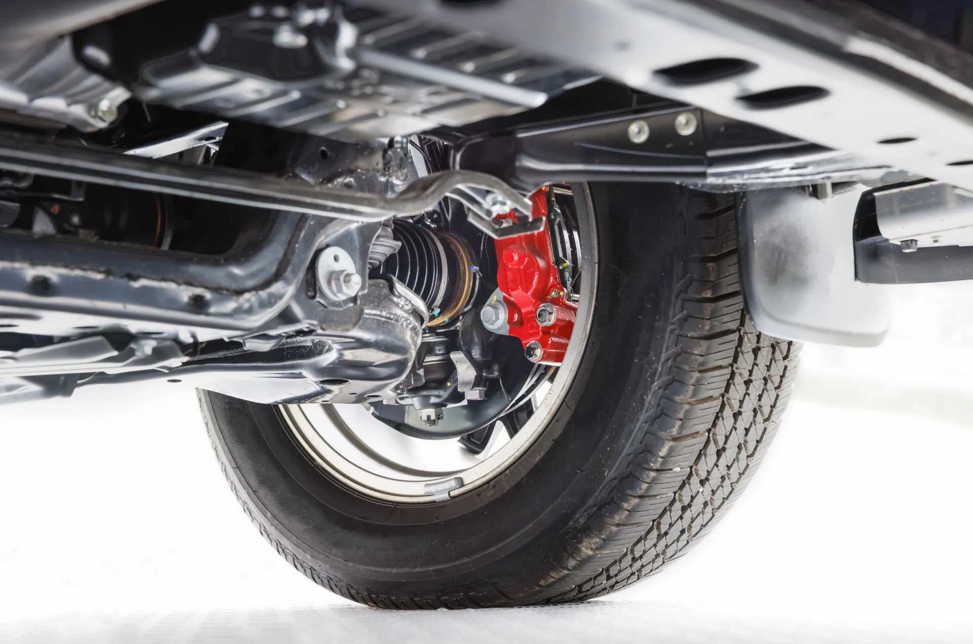 A close up of the underside of a car with a red brake caliper.