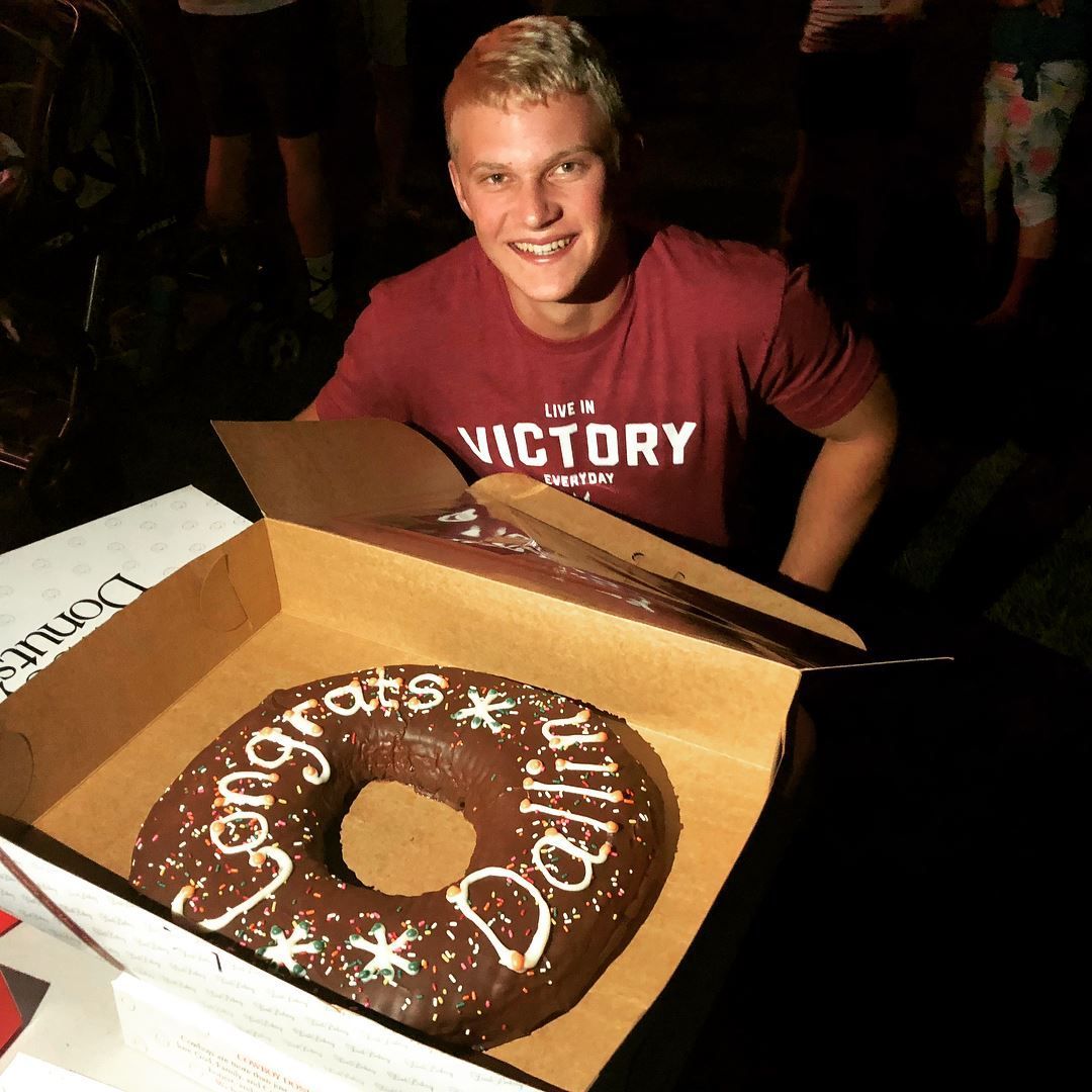 Man holding a donut cake that says 