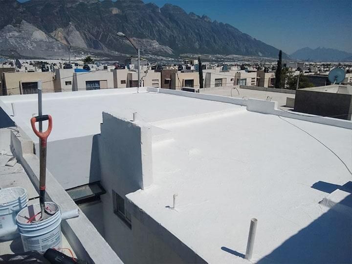 Techo plano pintado de blanco con montañas de fondo y barrio residencial.