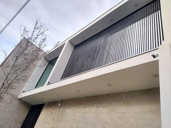 Edificio moderno de color blanco con fachada de listones negros y una pequeña ventana.