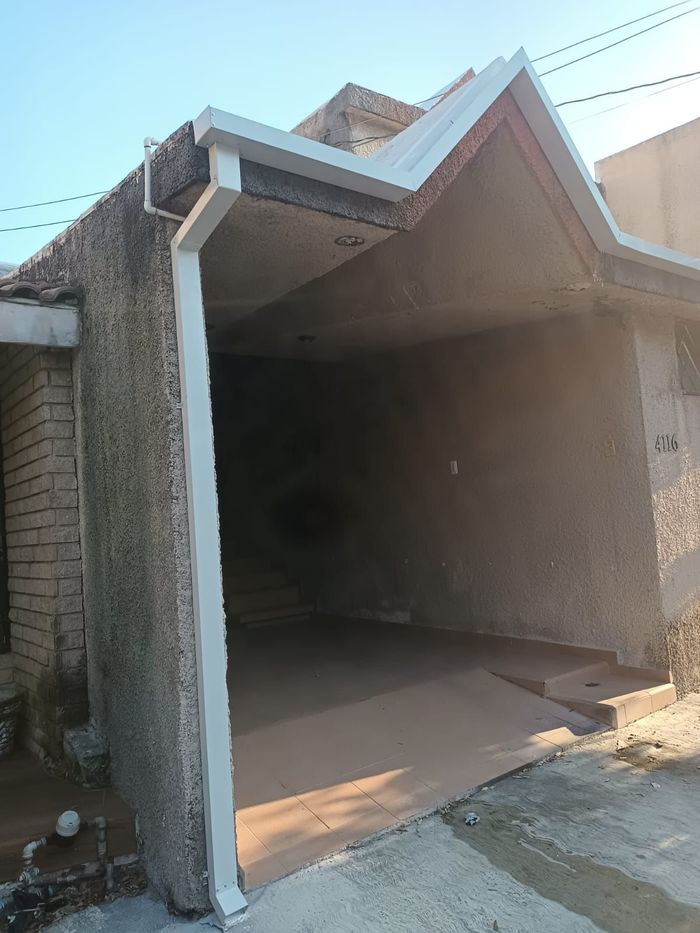 Cochera cubierta con piso marrón, paredes de estuco gris, molduras blancas y un pequeño techo.