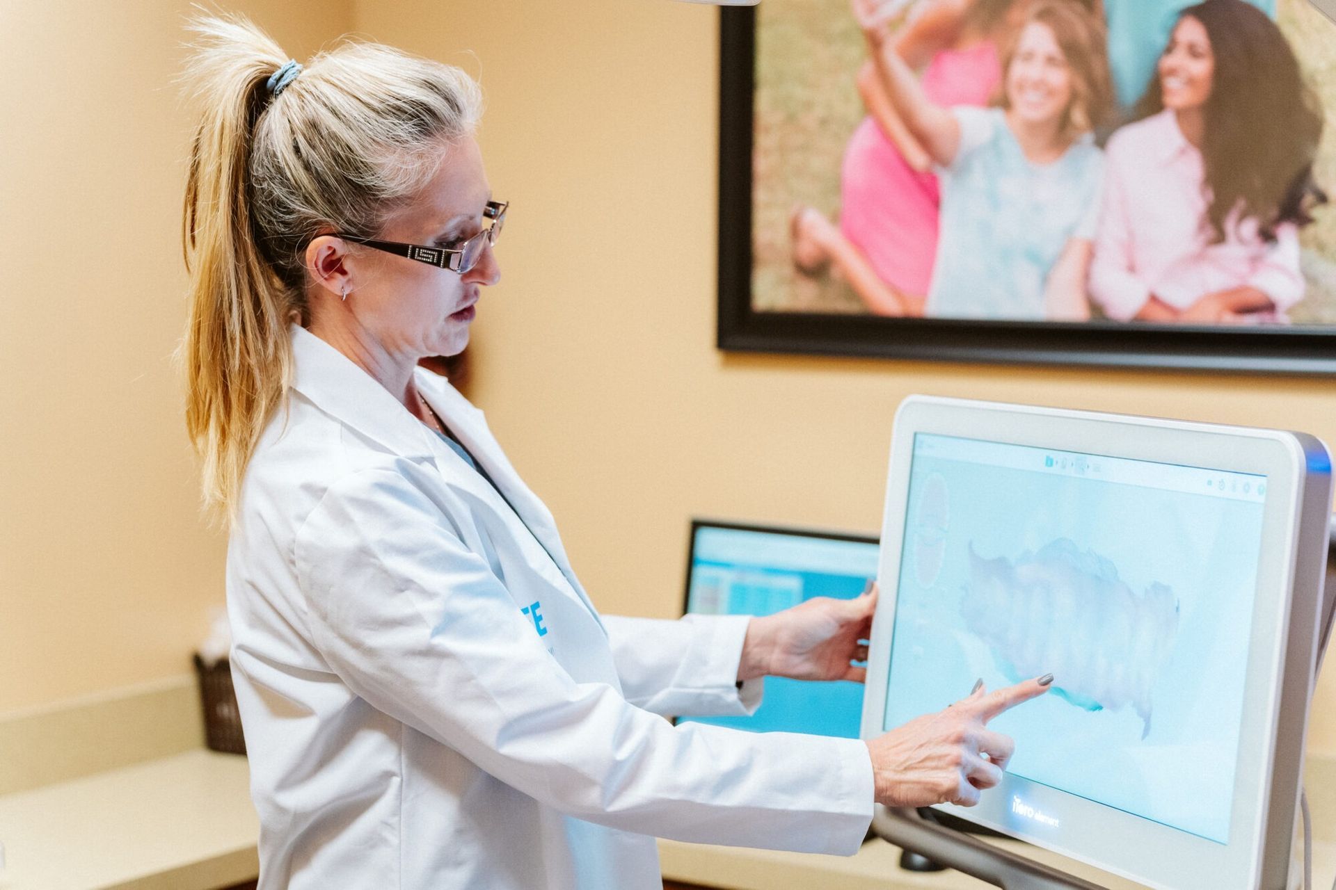 Dentist pointing at a tooth scan on a monitor in a dental office.