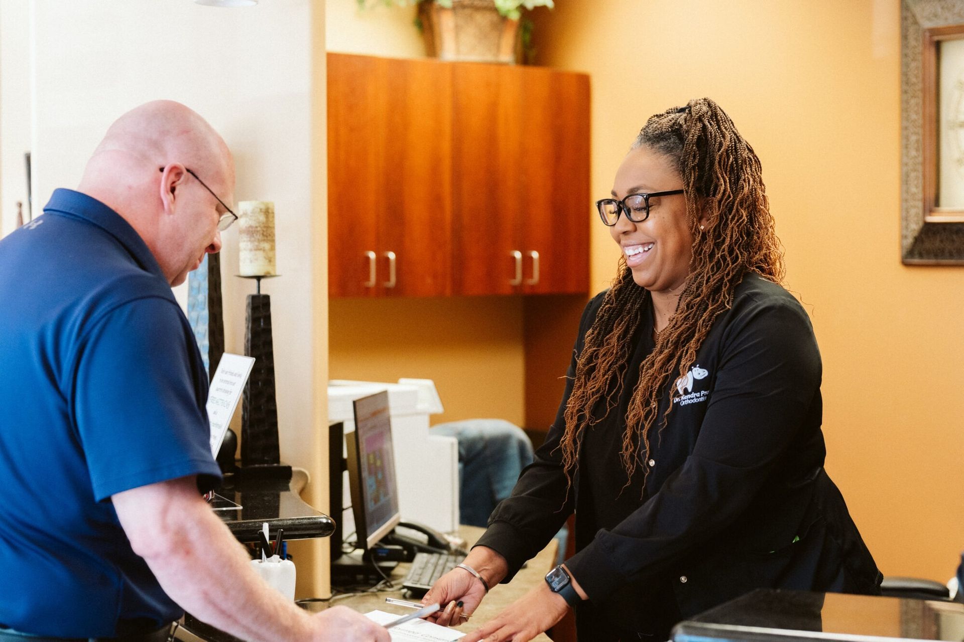 Man at a desk in a medical office, interacting with a smiling employee.