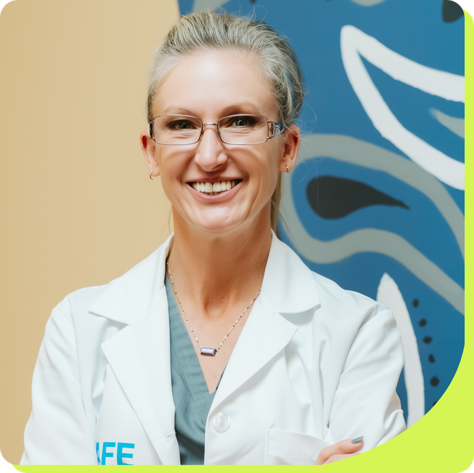 Woman wearing glasses and lab coat smiles.