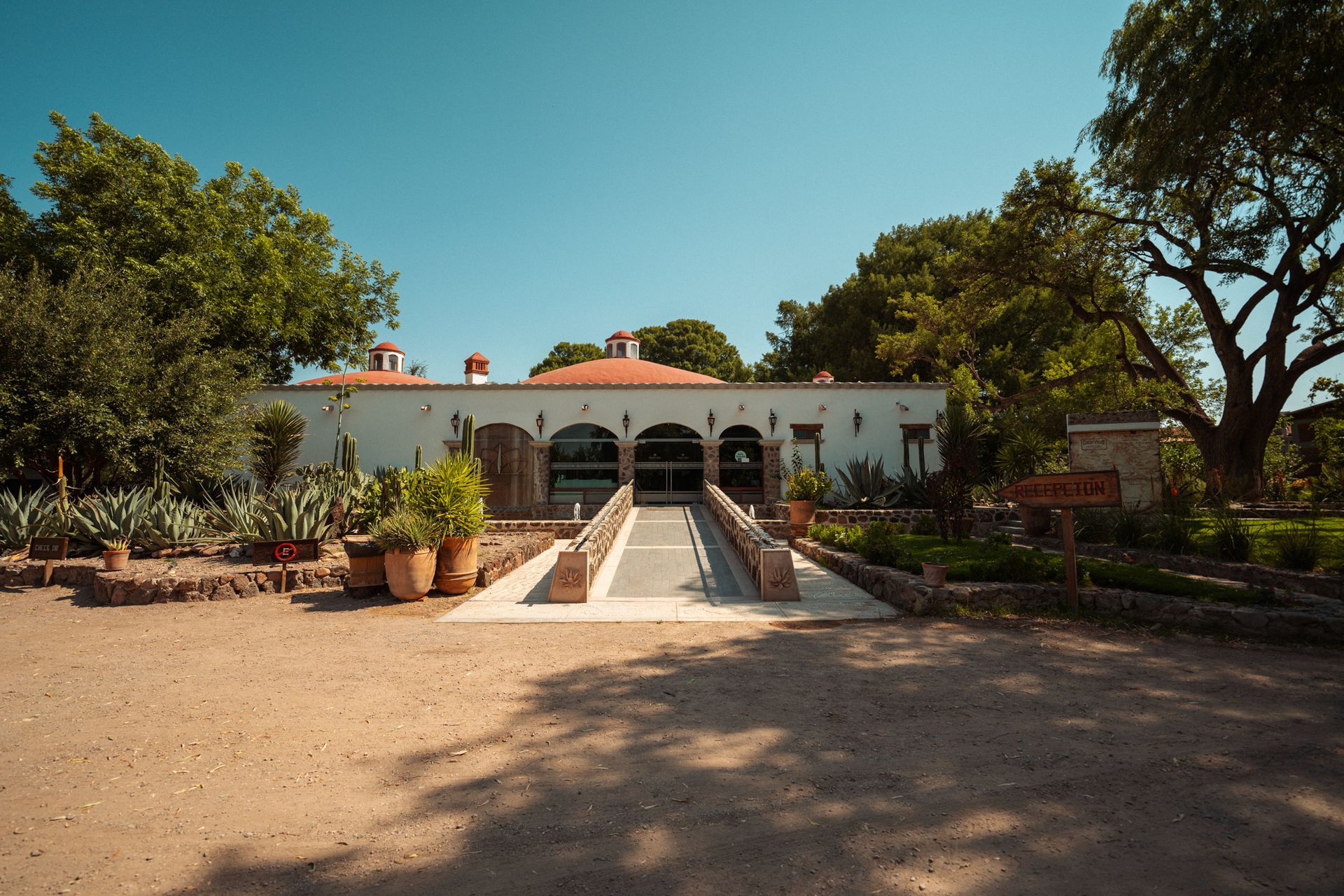 Edificio blanco con puerta de entrada arqueada y tejado de tejas rojas,
