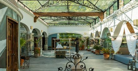 An interior courtyard with a glass roof, white arches, and potted plants.