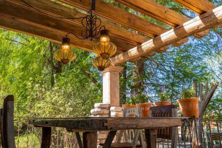 Outdoor dining area with wooden table, pergola, and hanging amber lights.