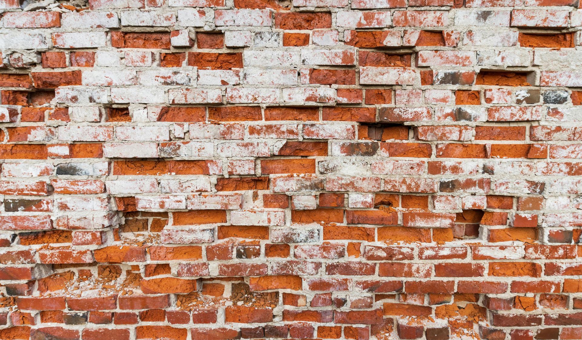 Brick wall repair needed - extensive masonry damage with missing bricks and failed mortar joints