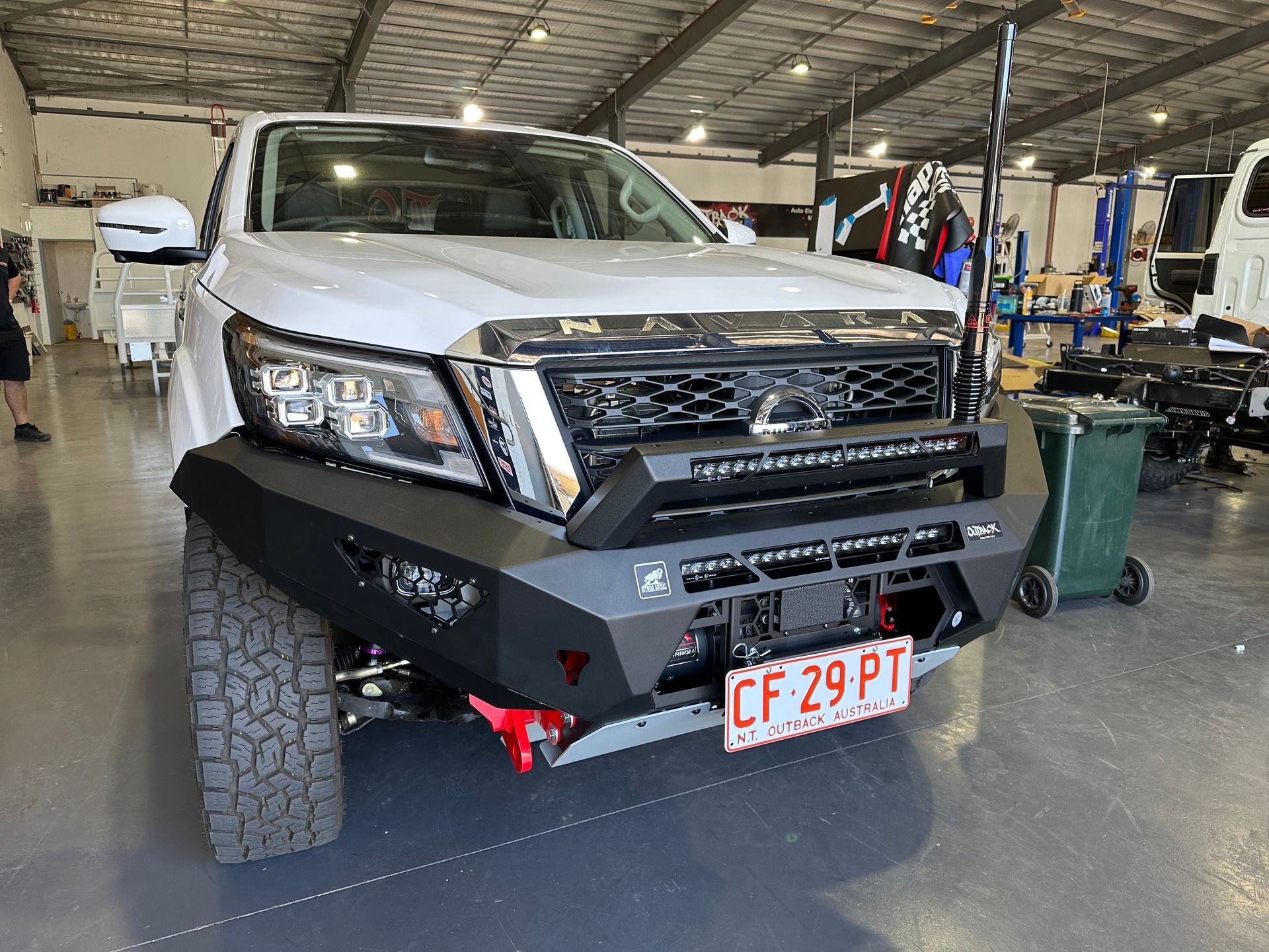 White pickup truck with off-road bumper and tires parked in a garage, front view  — Outback Auto NT in Berrimah, NT