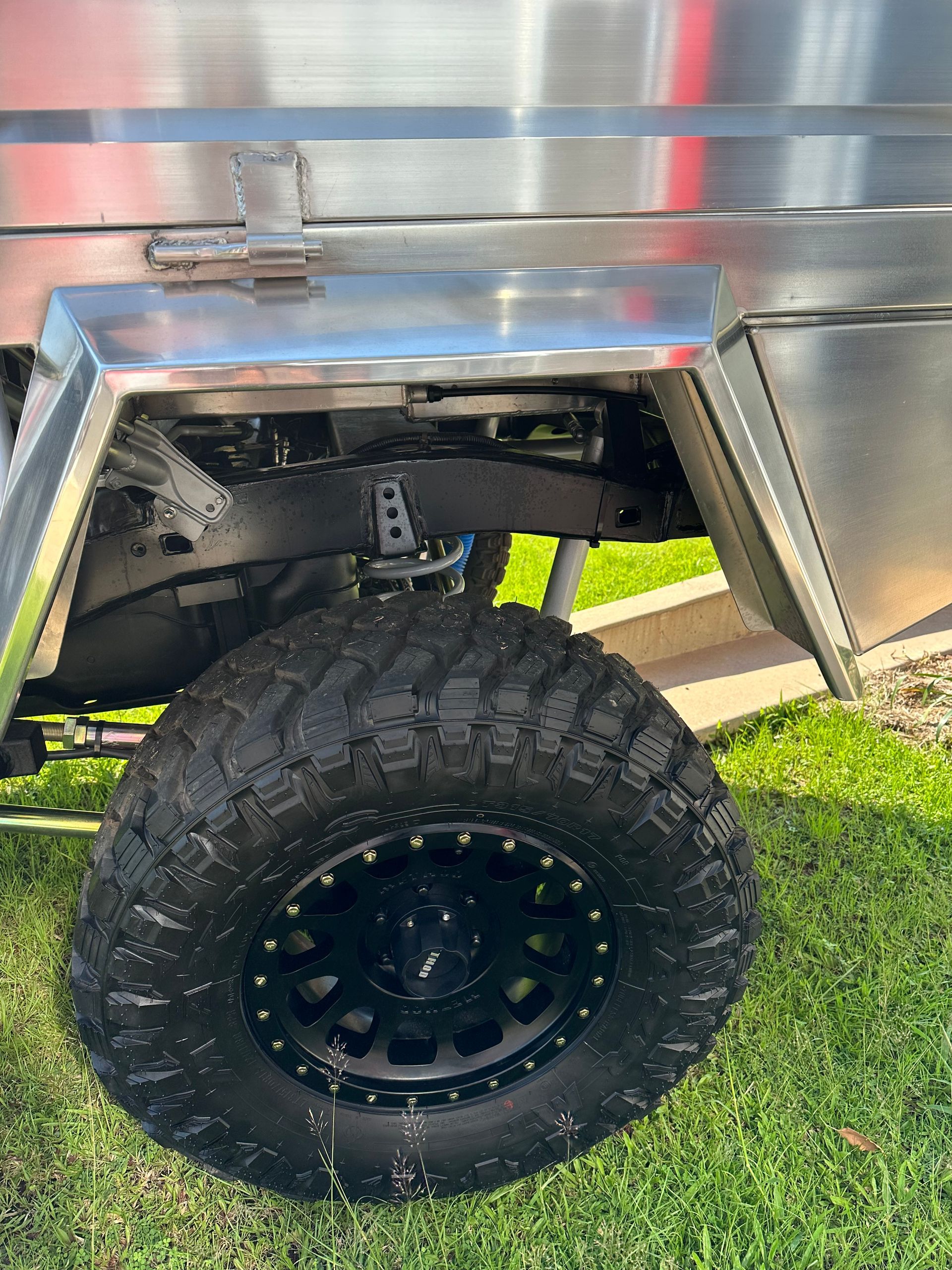 Black off-road tire under a shiny silver trailer on grass  — Outback Auto NT in Berrimah, NT