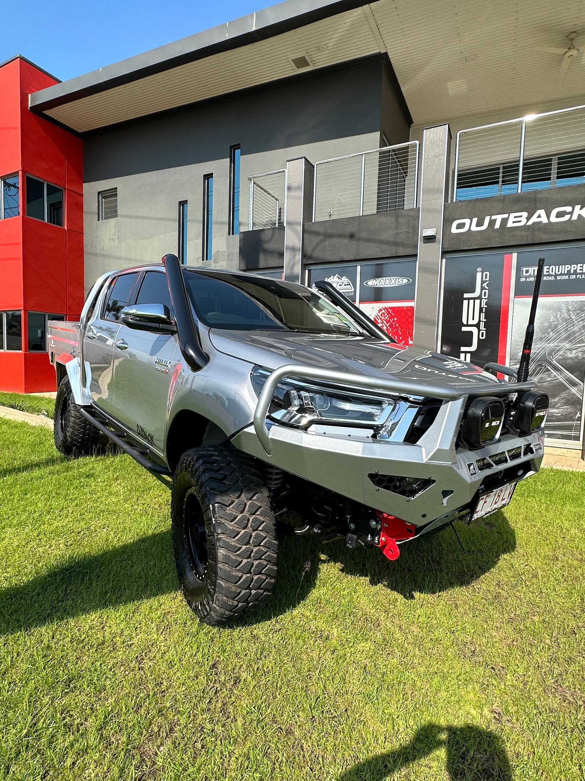 Silver off-road pickup truck with a bull bar parked on grass outside an Outback-branded building. — Outback Auto NT in Berrimah, NT