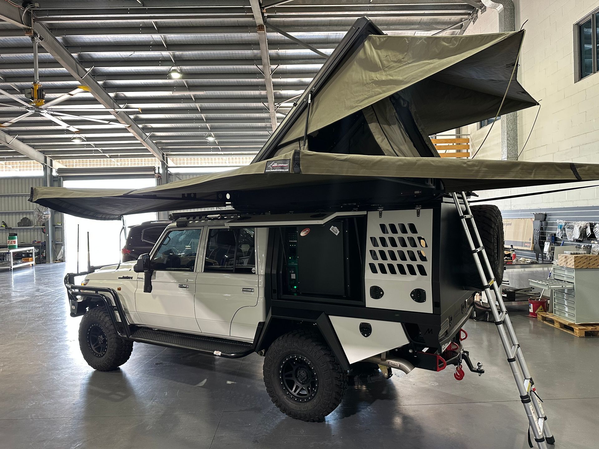 Off-road camper truck with pop-up roof tent parked indoors in a workshop — Outback Auto NT in Berrimah, NT