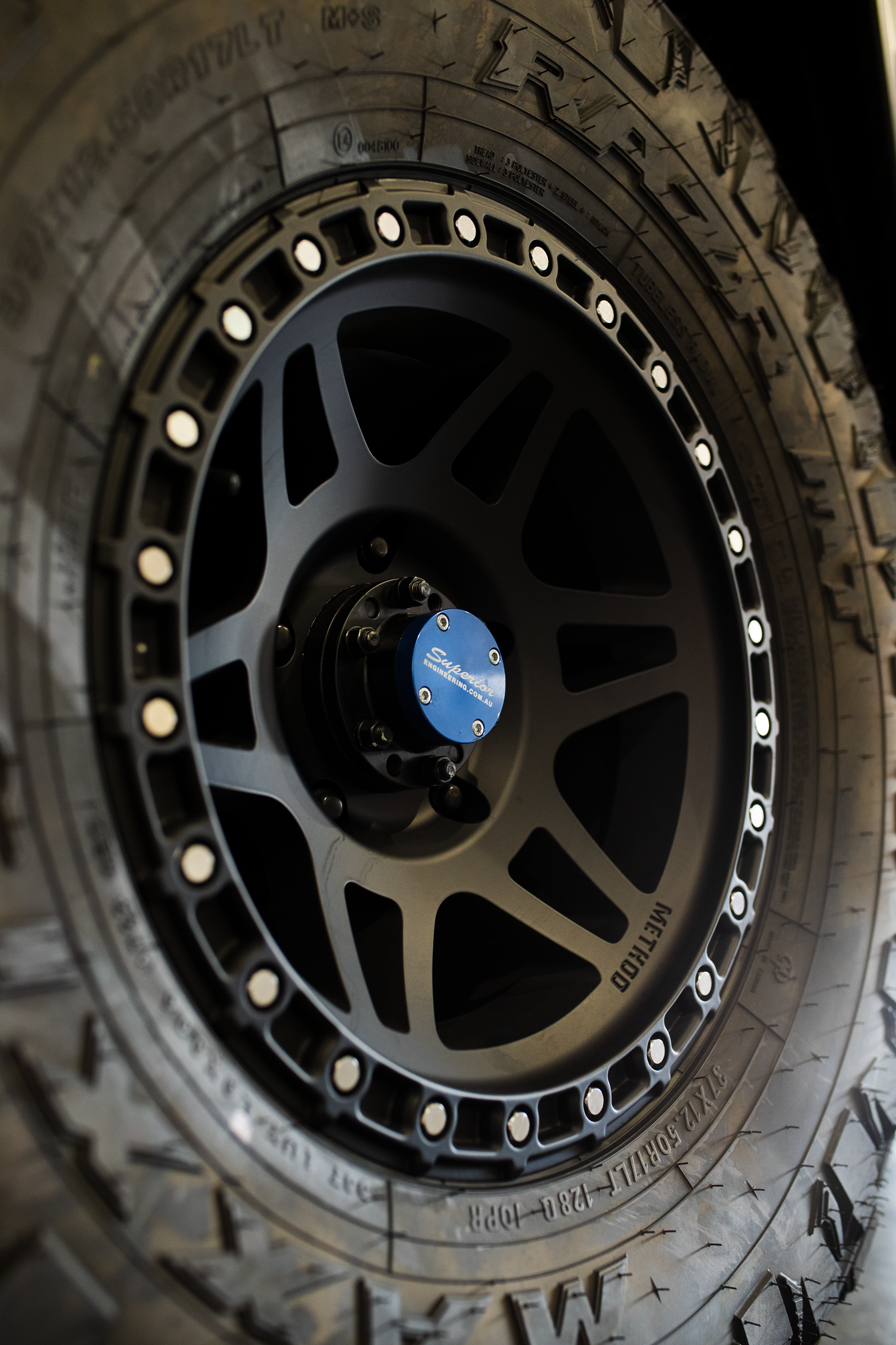 Black off-road tire on a matte black alloy wheel with blue center cap and silver bolt ring  — Outback Auto NT in Berrimah, NT
