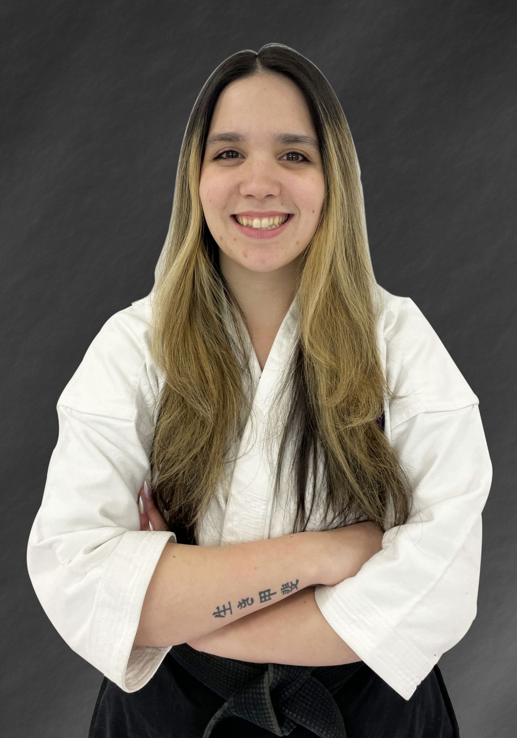 A man in a black karate uniform is standing with his arms crossed.
