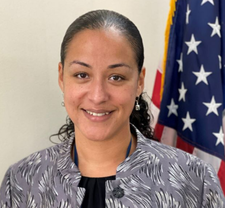 A woman is smiling in front of an american flag