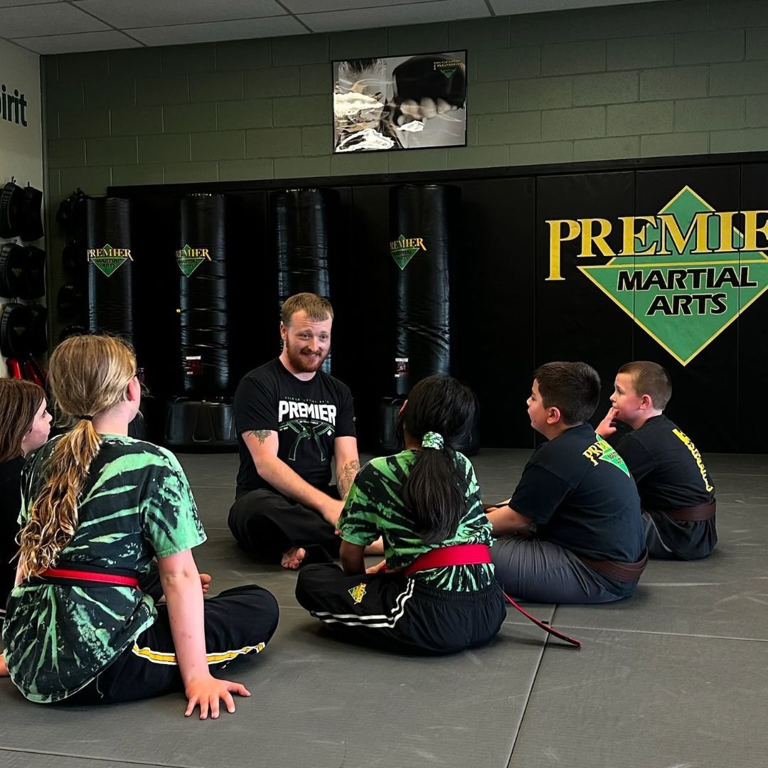 A group of children are practicing karate with a teacher in a gym.