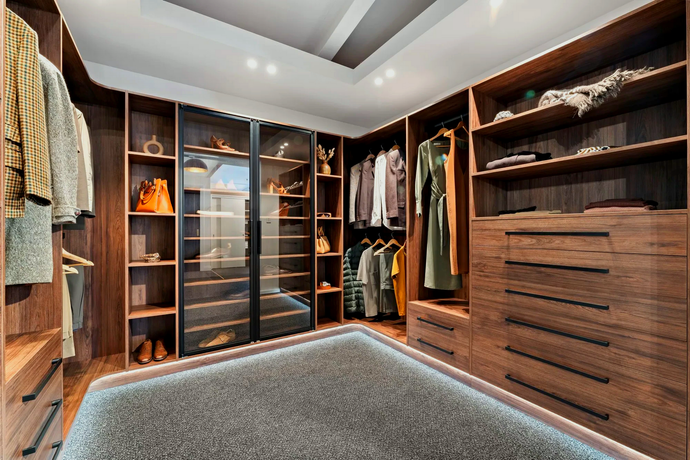 A walk in closet filled with lots of clothes and shoes.