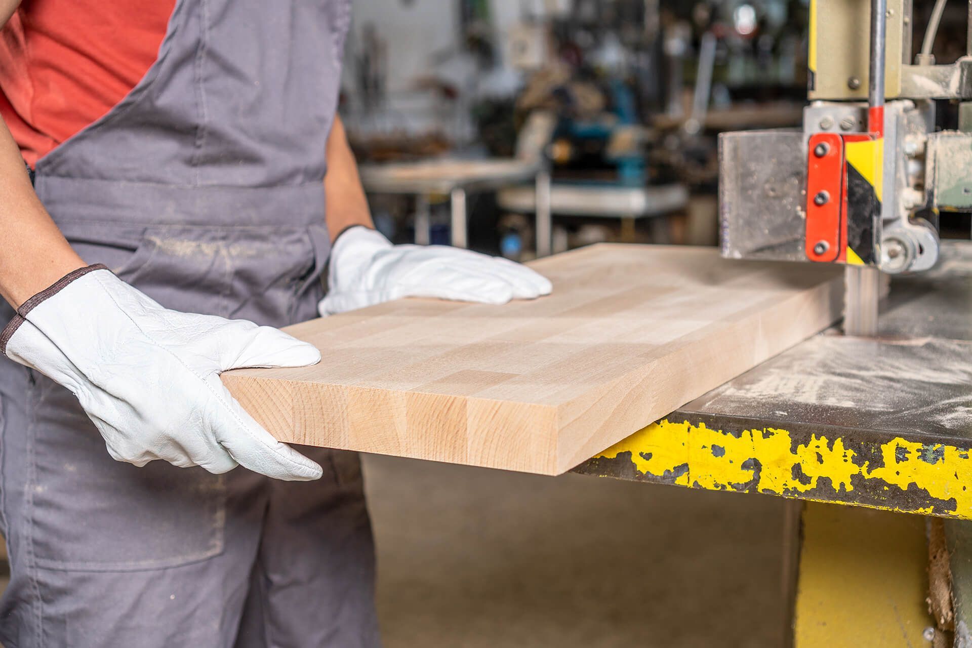 A man is cutting a piece of wood with a band saw.