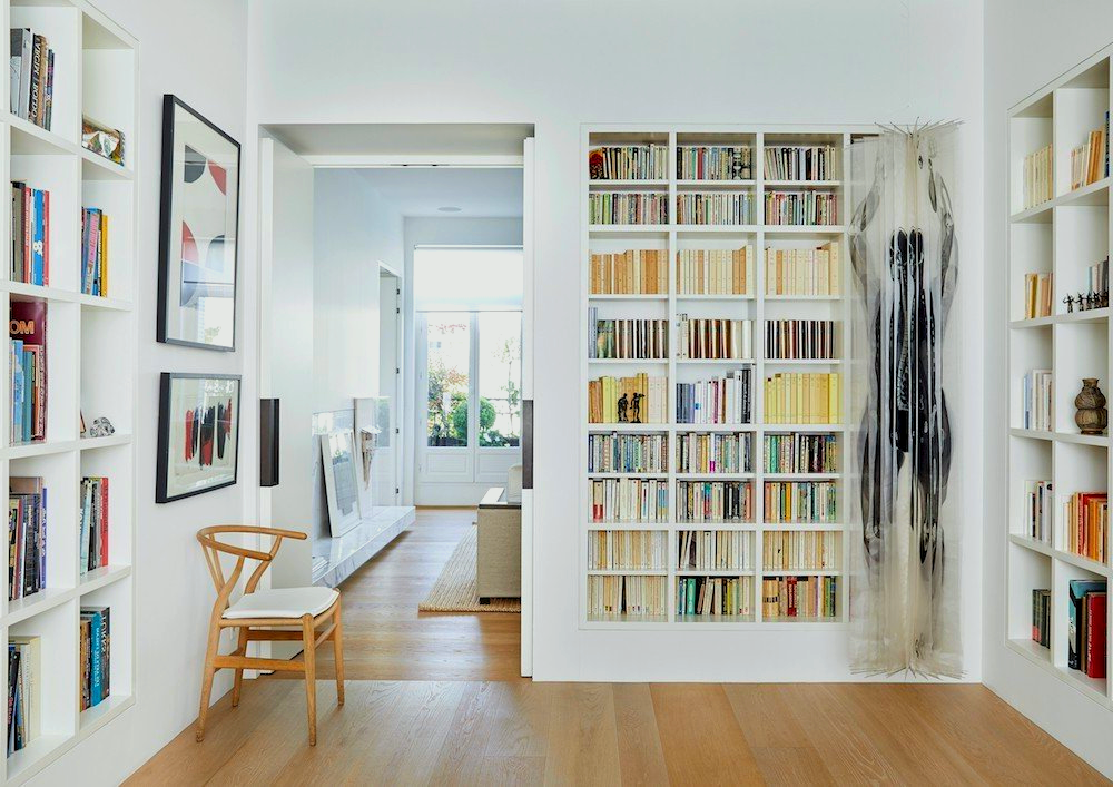 A living room filled with bookshelves and a chair.