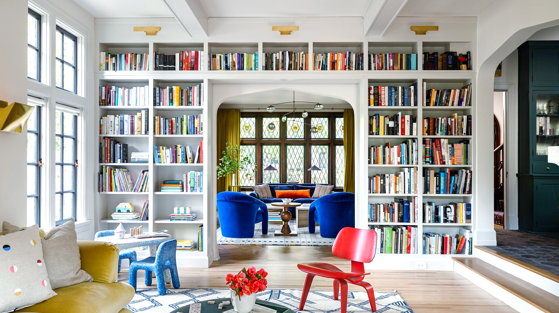 Living room with built-in bookshelves, vibrant colors, archway to sitting area, kids' table and chair.