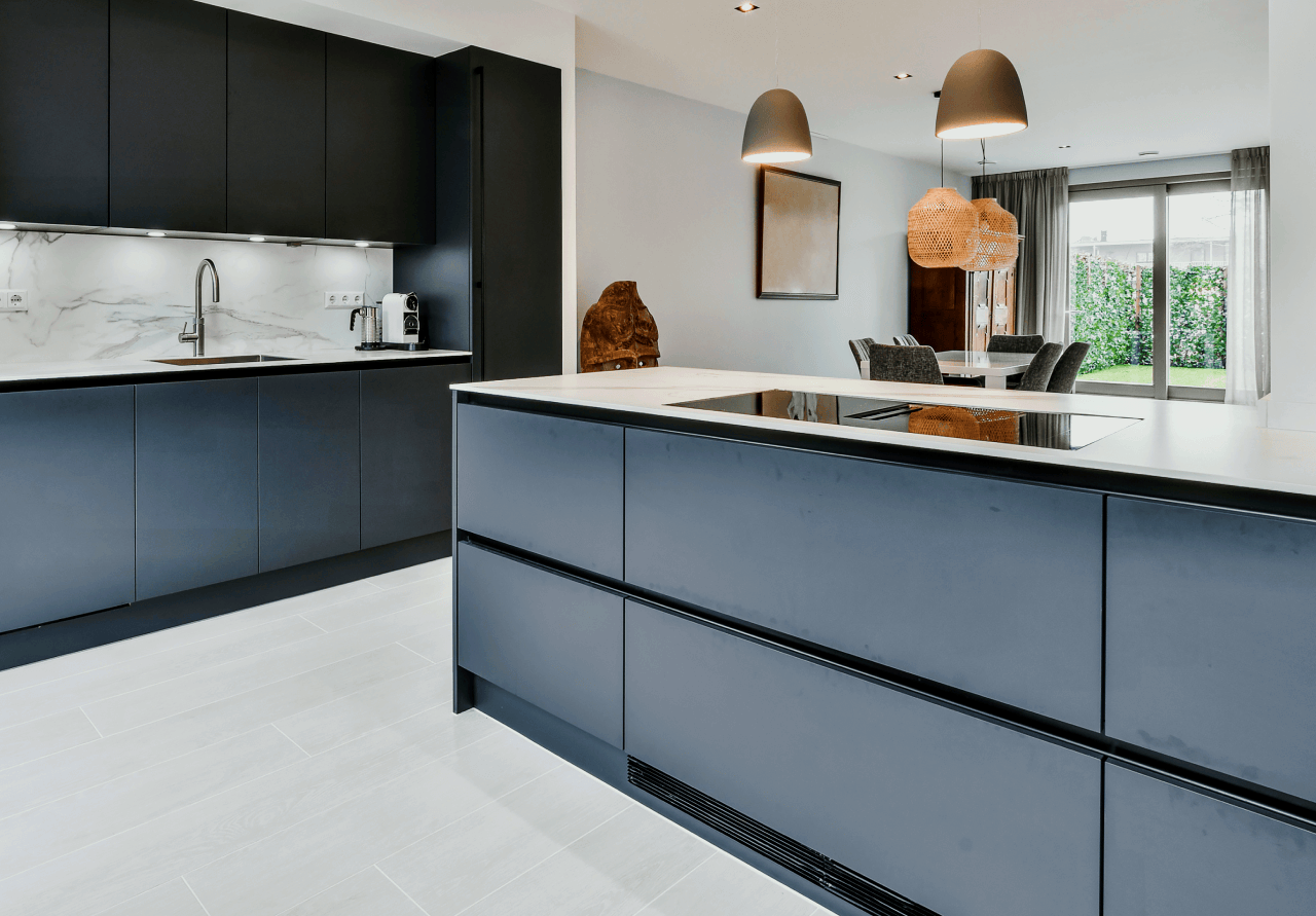 A kitchen with black cabinets and a large island in the middle.