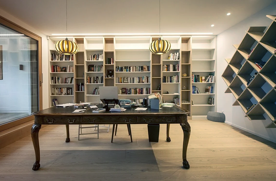 A room with a table, chairs, and shelves filled with books.