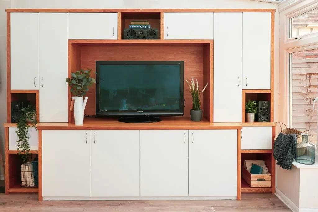 A living room with a flat screen tv on top of a wooden entertainment centre.