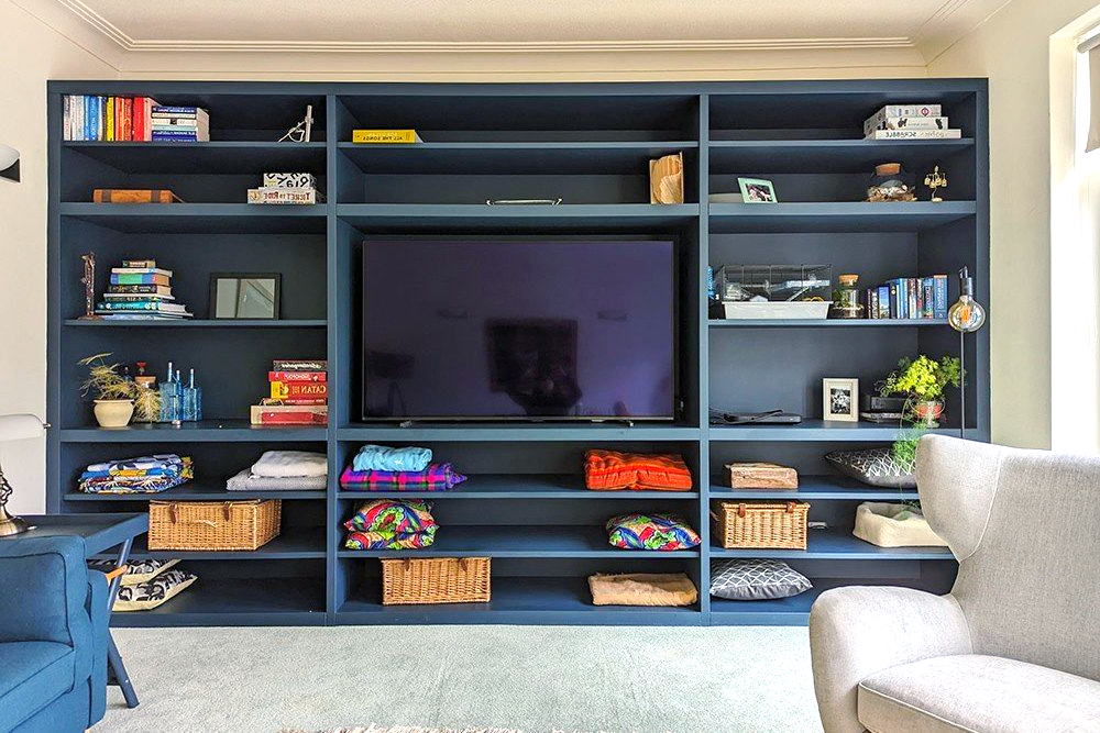 A living room with lots of shelves and a flat screen tv.