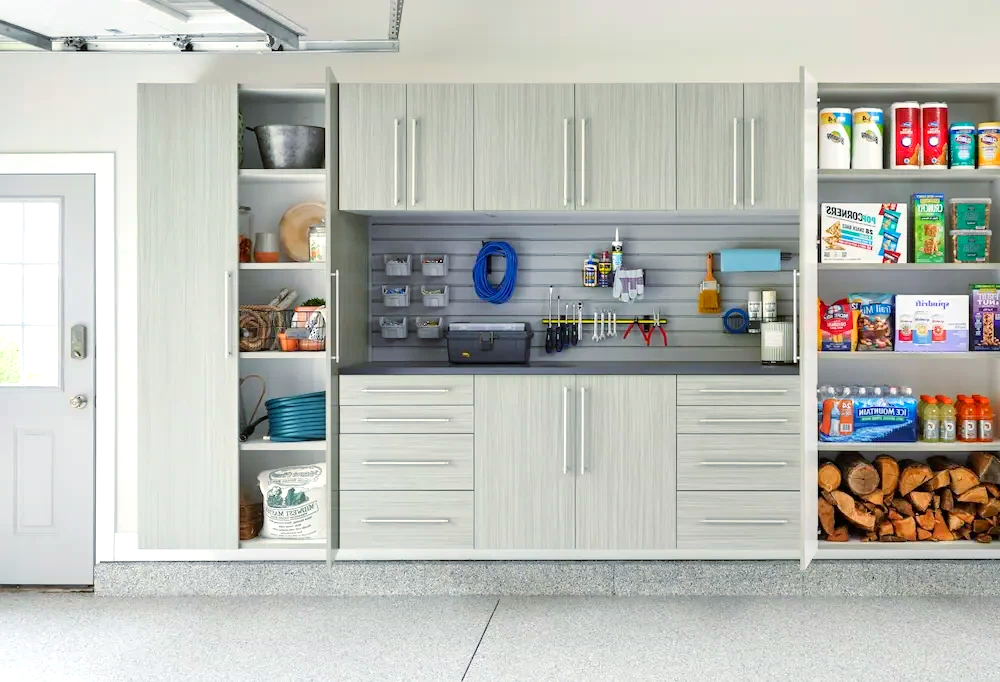 A garage with white cabinets, shelves, and a sink.