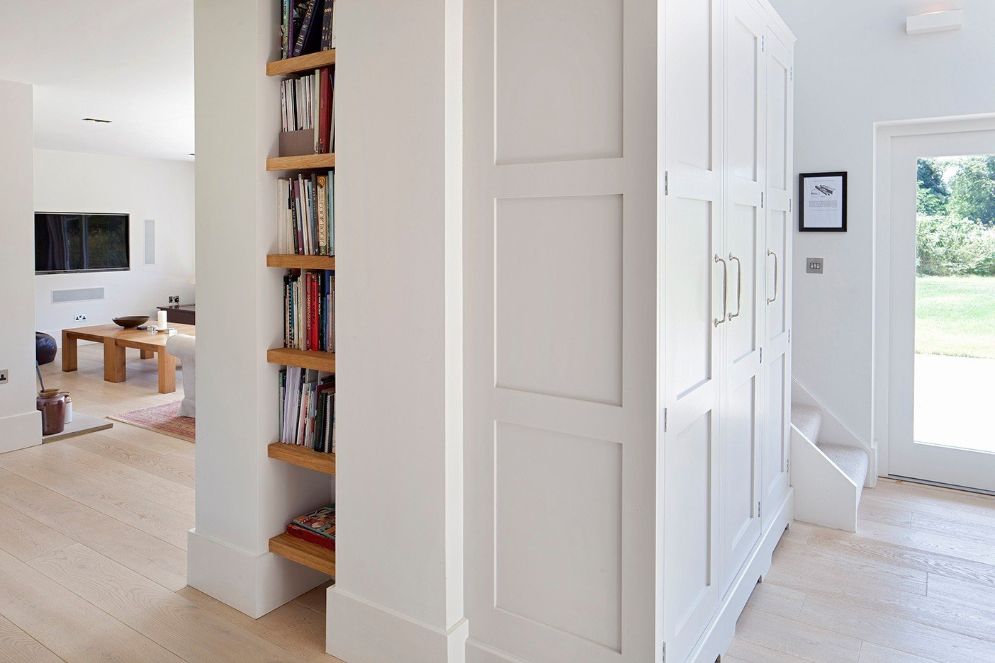 A hallway with white cabinets and wooden shelves.