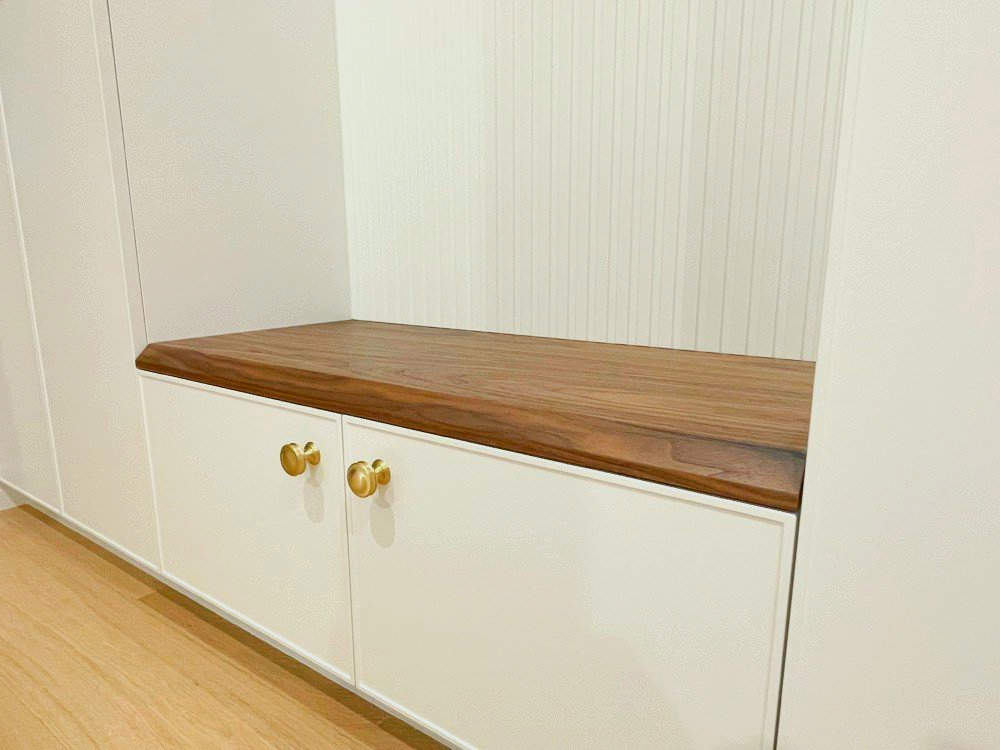 A white cabinet with a wooden top and gold handles.