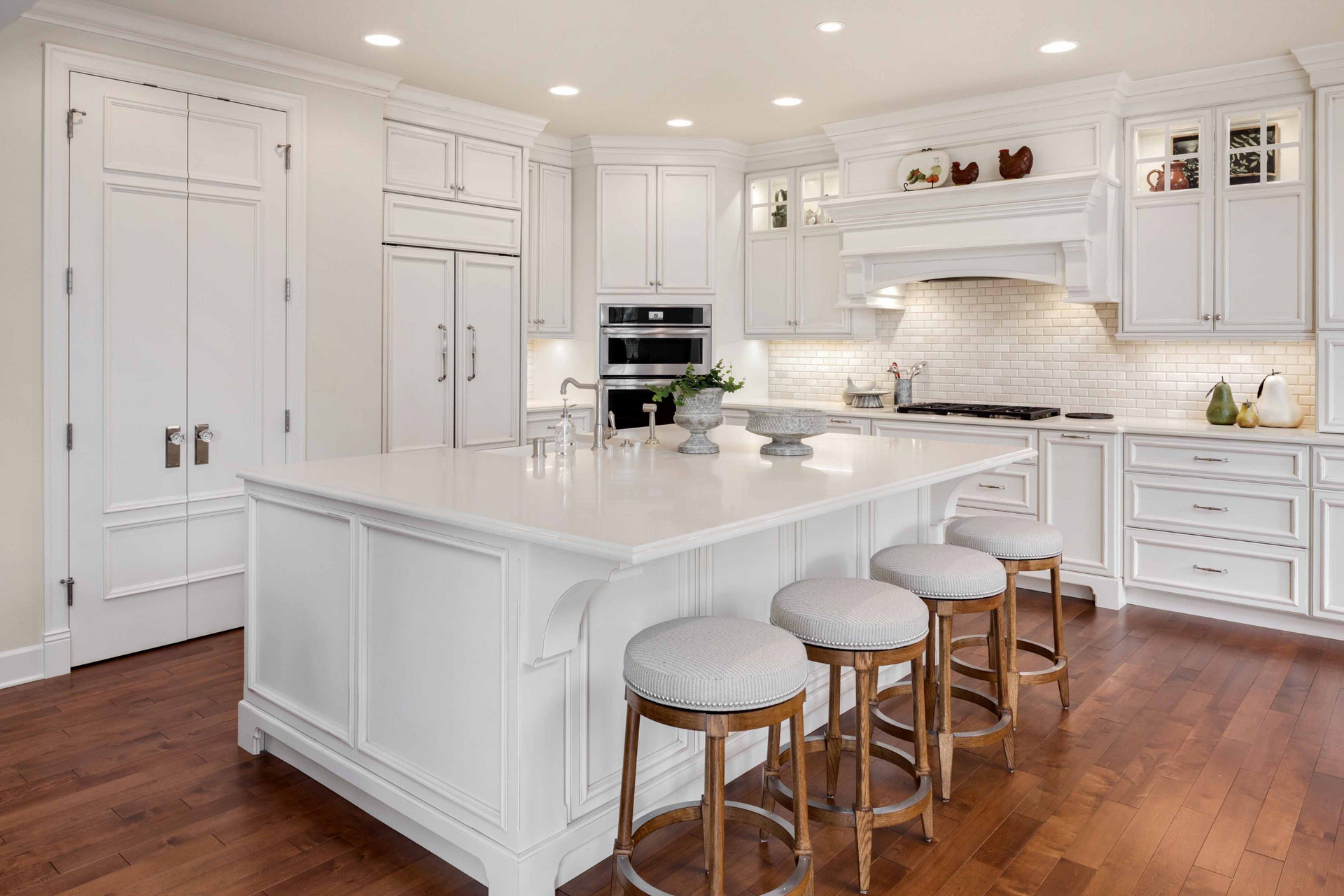 A brightly-lit kitchen with white cabinets and a large benchtop