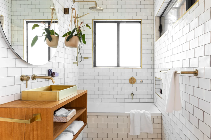 A bathroom with white tiles, a sink, a tub, a mirror and a window.