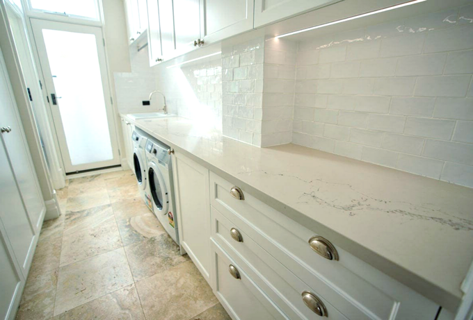 A laundry area with two washing machines and white cabinetry.